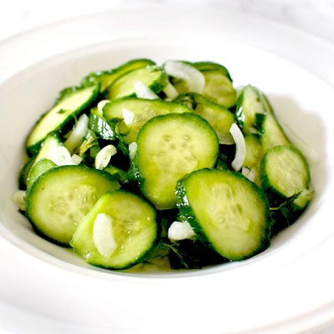 cucumber salad in a white bowl on a white marble counter