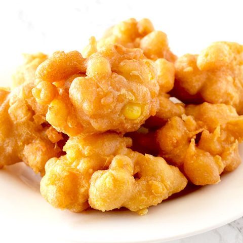 Corn fritters on a white plate on a white marble counter