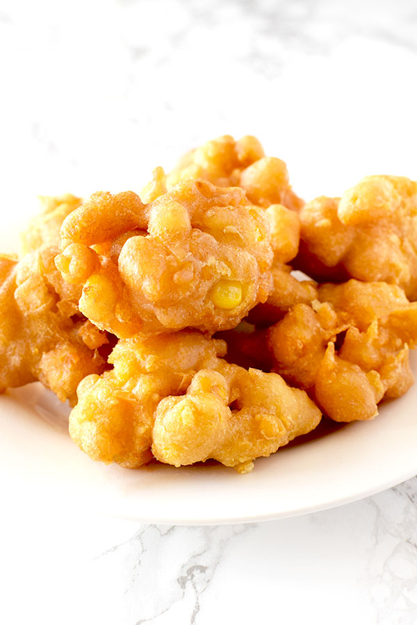 Corn fritters on a white plate on a white marble counter