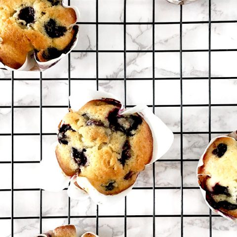 blueberry muffins on a black cooling rack on a white marble counter