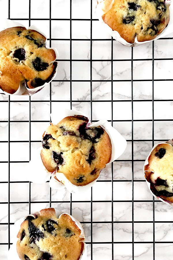 blueberry muffins on a black cooling rack on a white marble counter