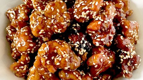 Chinese sesame chicken in a white bowl on a white marble counter