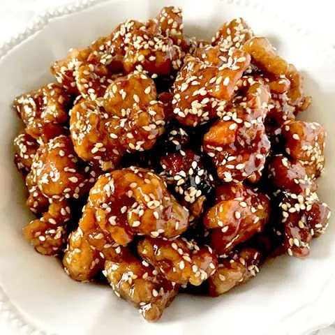 Chinese sesame chicken in a white bowl on a white marble counter