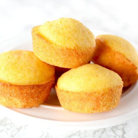 cornbread muffins piled on a plate on a white marble counter