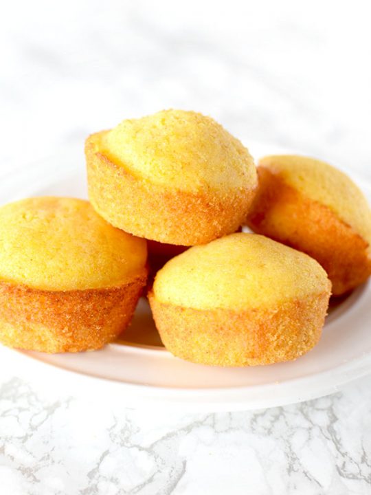 cornbread muffins piled on a plate on a white marble counter