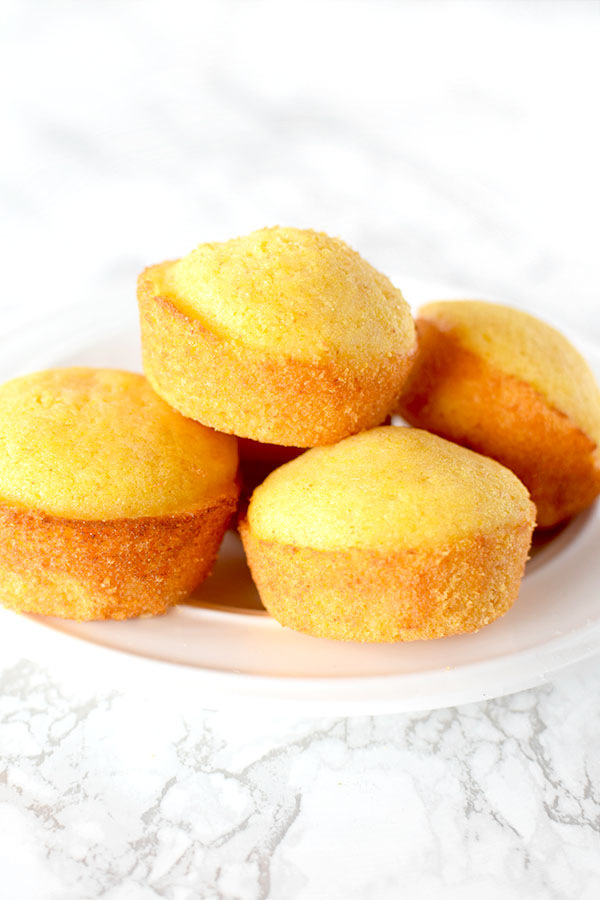 cornbread muffins piled on a plate on a white marble counter