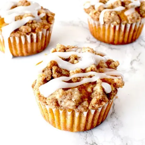 pumpkin muffins with streusel and icing on a white marble counter