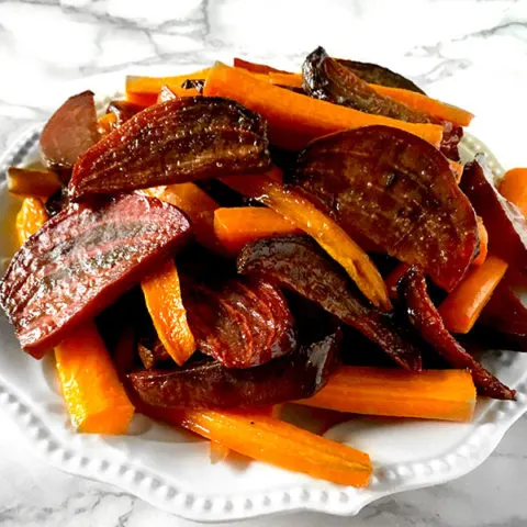 roasted beets and carrots on a white plate on a white marble counter