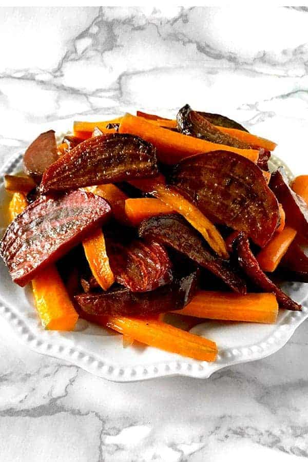 roasted beets and carrots on a white plate on a white marble counter
