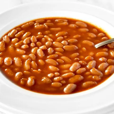 a white bowl filled with Israeli bean soup on a white marble counter