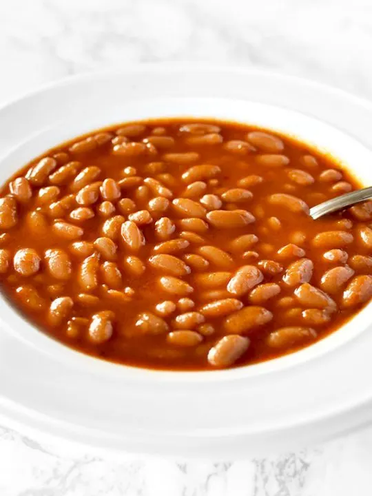 a white bowl filled with Israeli bean soup on a white marble counter