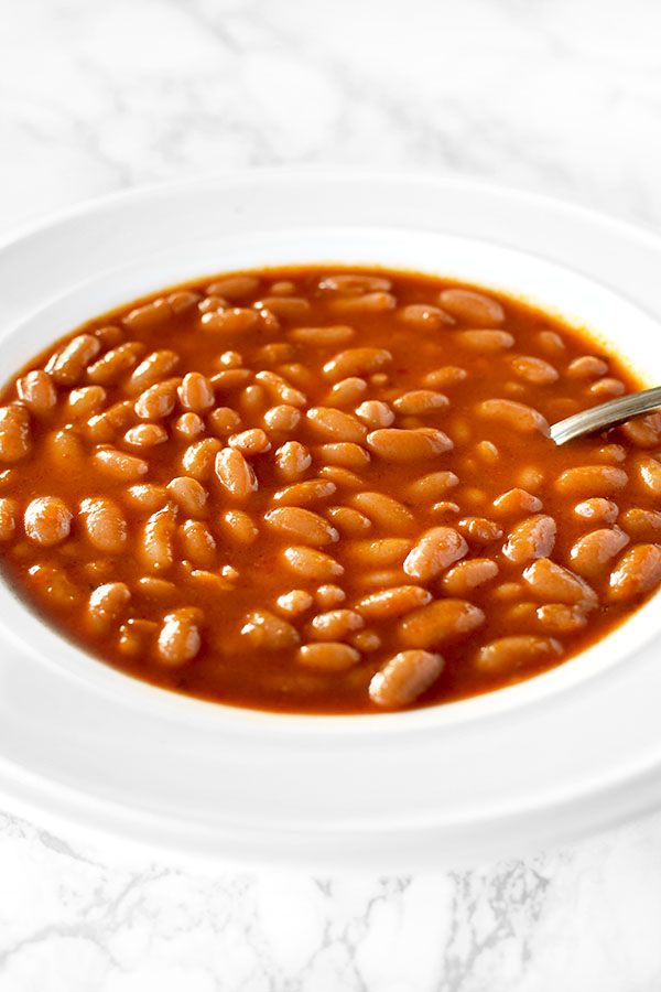 a white bowl filled with Israeli bean soup on a white marble counter