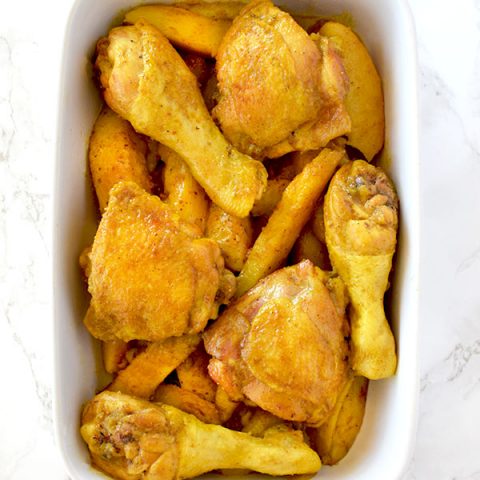 Yellow chicken and potatoes in a ceramic baking dish