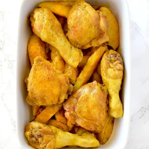 Yellow chicken and potatoes in a ceramic baking dish