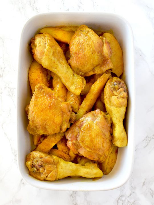 Yellow chicken and potatoes in a ceramic baking dish