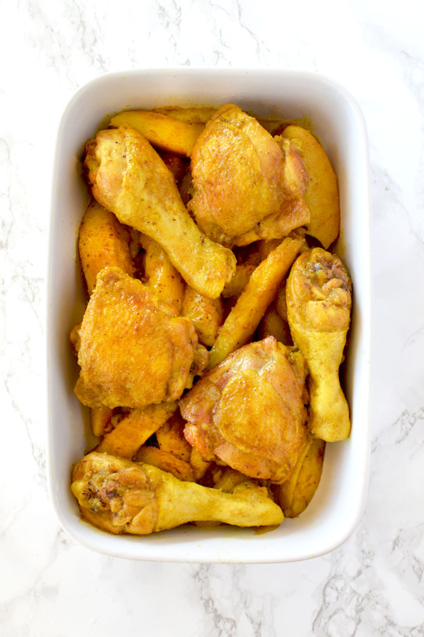 Yellow chicken and potatoes in a ceramic baking dish