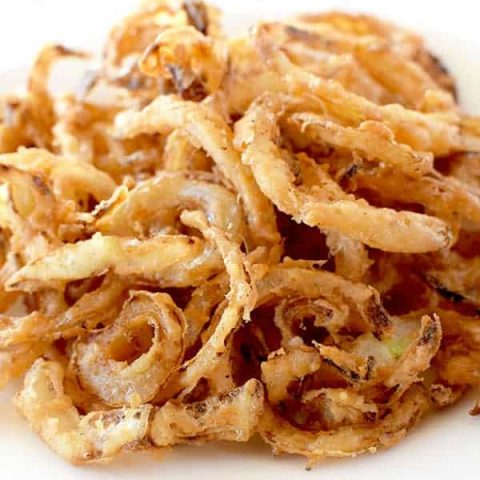 Homemade fried onions on a white plate on a white marble counter