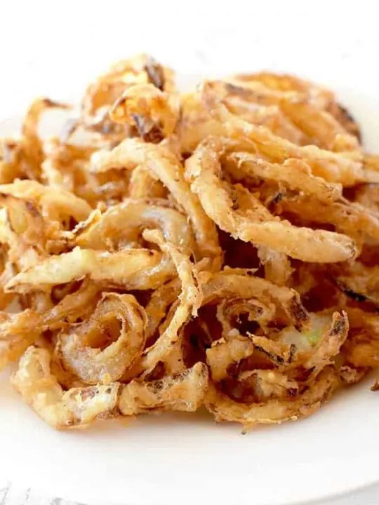 Homemade fried onions on a white plate on a white marble counter