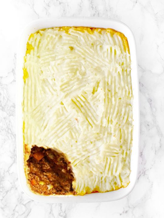 dairy free shepherd's pie or cottage pie in a white casserole dish on on a white marble counter