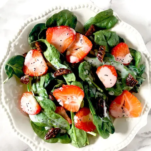 Strawberries and candied pecans on a bed of baby spinach drizzled with poppy seed dressing