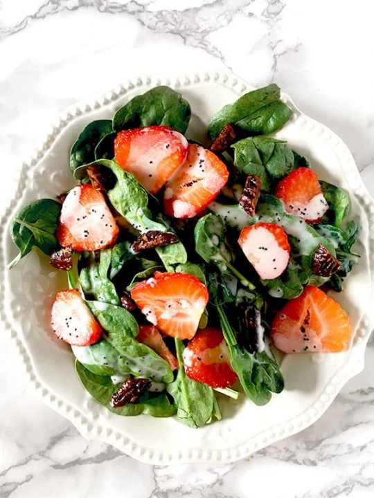 Strawberries and candied pecans on a bed of baby spinach drizzled with poppy seed dressing