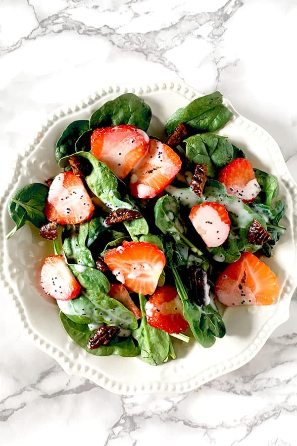 Strawberries and candied pecans on a bed of baby spinach drizzled with poppy seed dressing