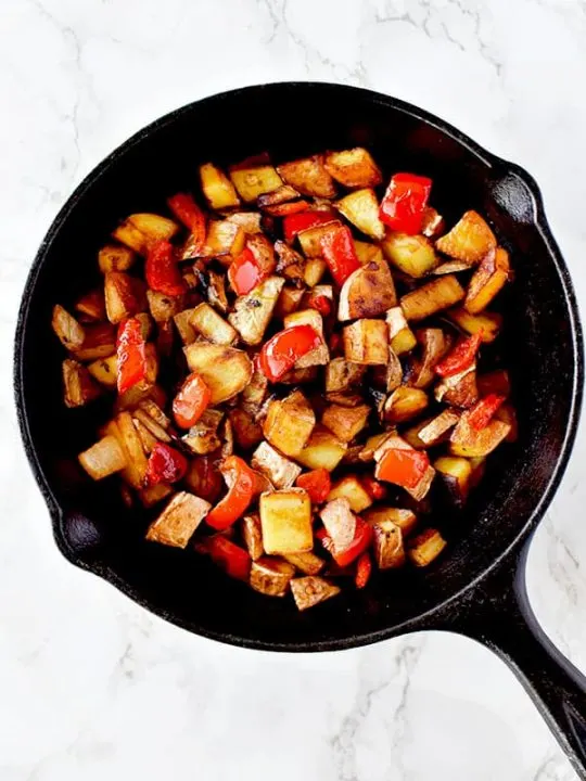 Breakfast hash of potatoes, peppers, and onions in a cast iron pan