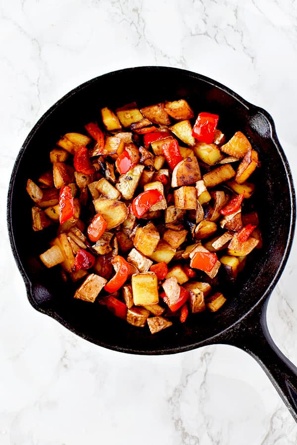 Breakfast hash of potatoes, peppers, and onions in a cast iron pan