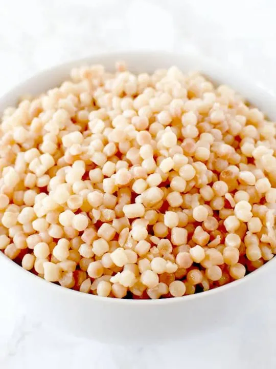 bowl of pearl couscous on a white marble counter