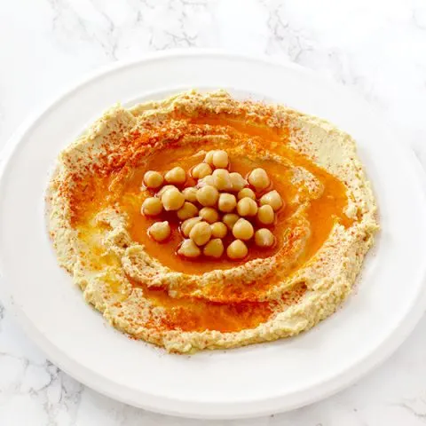 hummus in a plate on with oil, paprika, and chickpeas