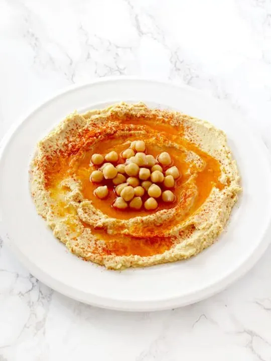 hummus in a plate on with oil, paprika, and chickpeas