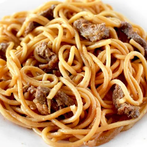 Beef lo mien on a white plate on a marble counter
