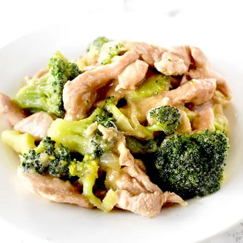 Chicken and broccoli on a white plate on a white marble counter