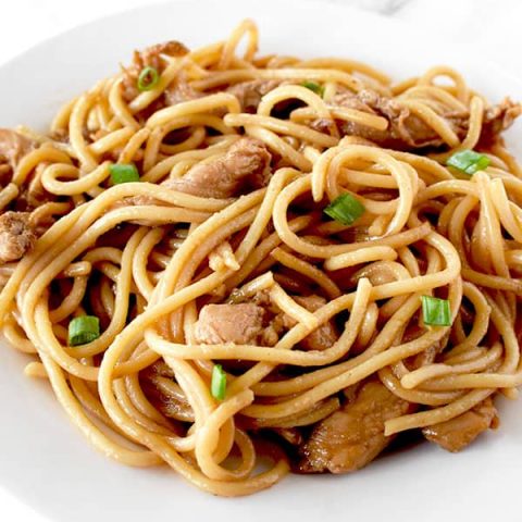 Chicken lo mein on a whit plate on a white marble counter
