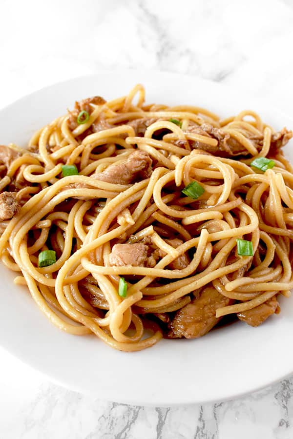 Chicken lo mein on a whit plate on a white marble counter