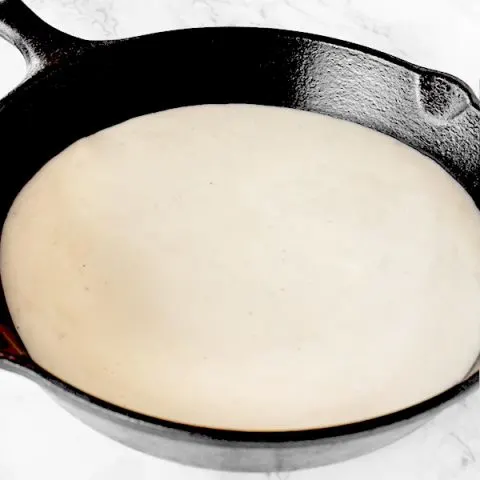 Country gravy in a cast iron pan on a white marble counter
