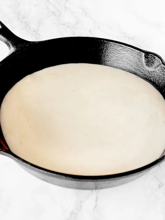 Country gravy in a cast iron pan on a white marble counter