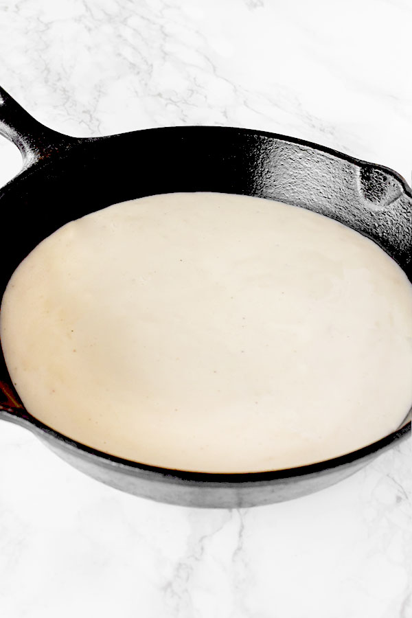 Dairy Free Béchamel Sauce or White Sauce in a cast iron pan on a white marble counter