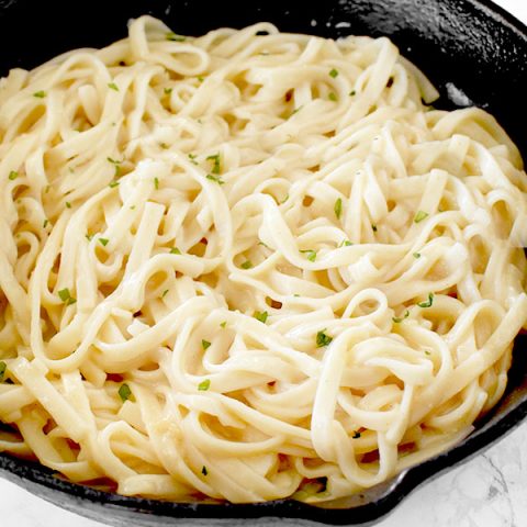 Dairy free fettucchine Alfredo in a cast iron skillet on a white marble counter