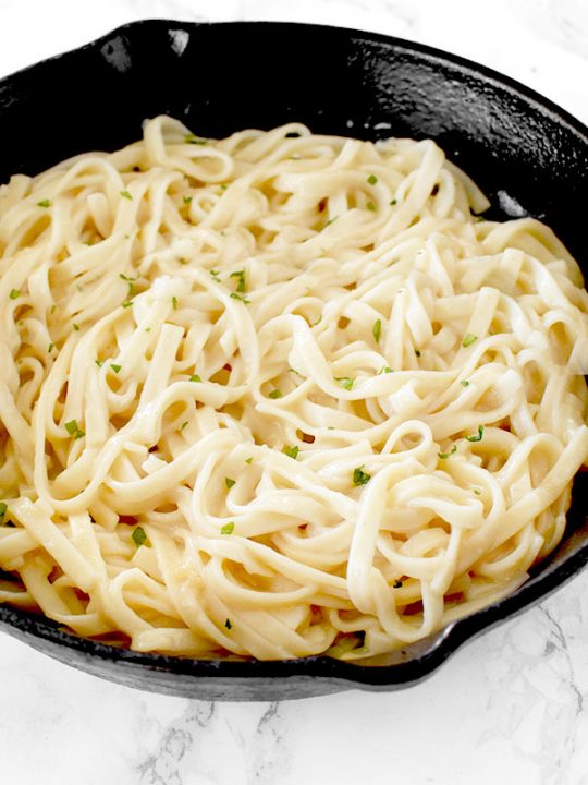 Dairy free fettucchine Alfredo in a cast iron skillet on a white marble counter