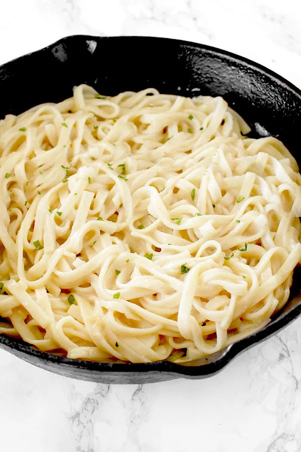 Dairy free fettucchine Alfredo in a cast iron skillet on a white marble counter