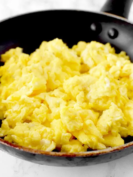 scrambled eggs in a frying pan on a marble counter