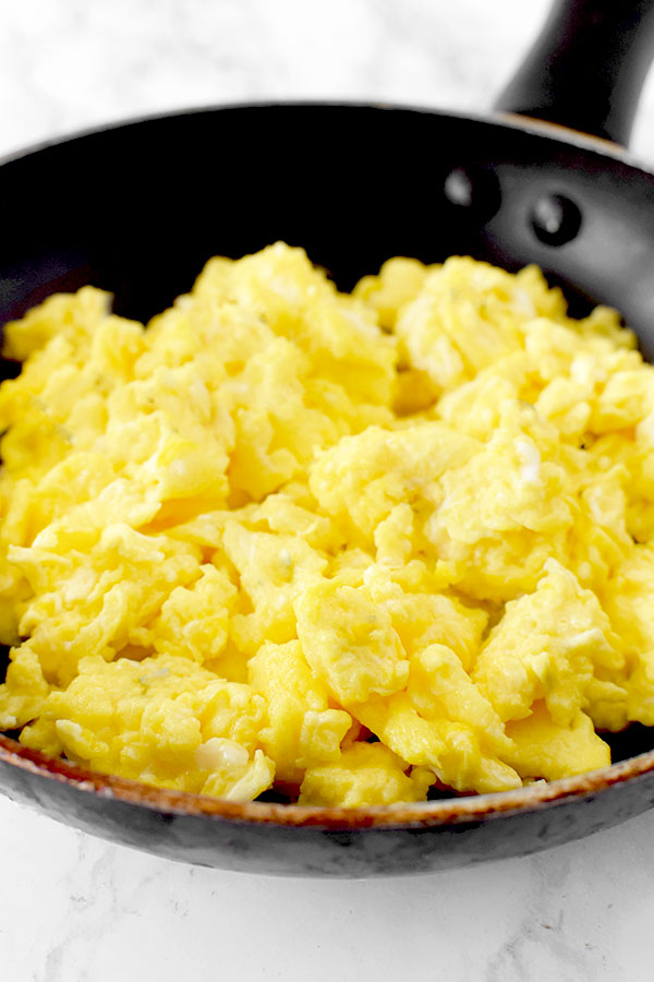 scrambled eggs in a frying pan on a marble counter