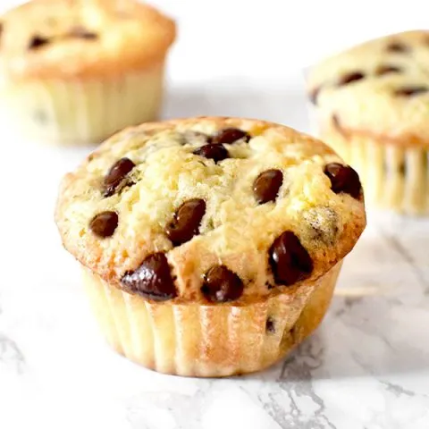 three chocolate chip muffins with oil on a marble counter