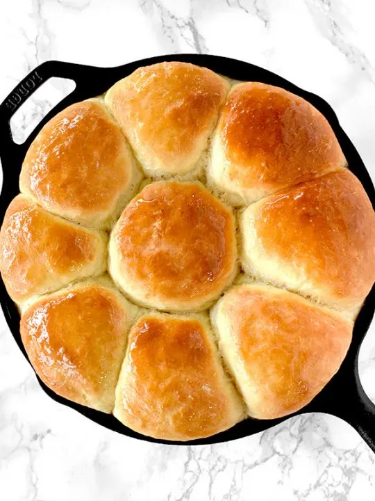 Dairy free dinner rolls in a cast iron skillet on a white marble counter