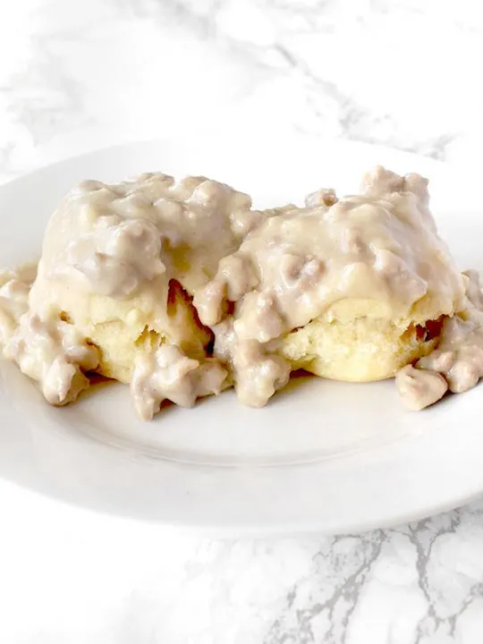 Dairy Free biscuits and gravy on a white plate on a white marble counter