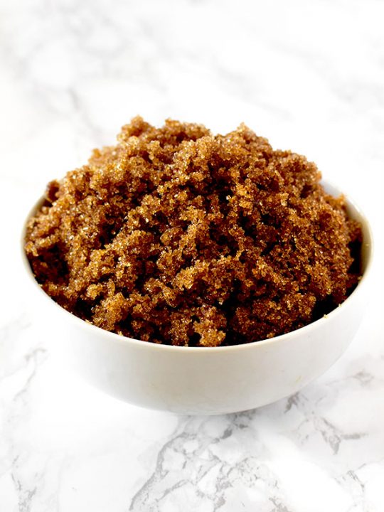 Dark brown sugar in a white bowl on a white marble counter