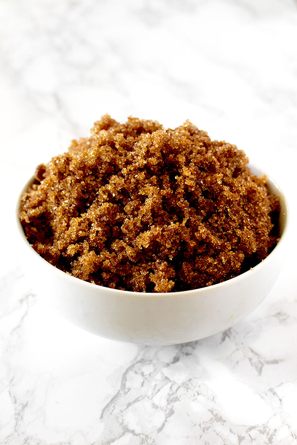 Dark brown sugar in a white bowl on a white marble counter