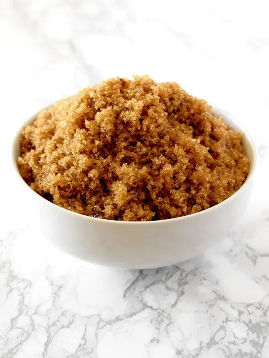 light brown sugar in a white bowl on a white marble counter
