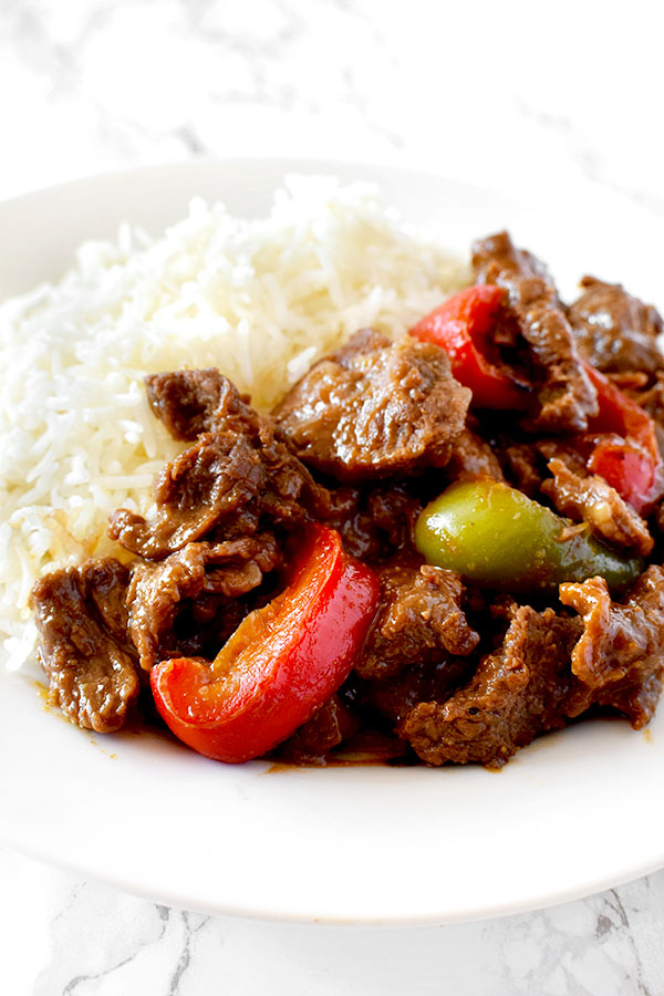 pepper steak and rice on a white plate on a white marble counter